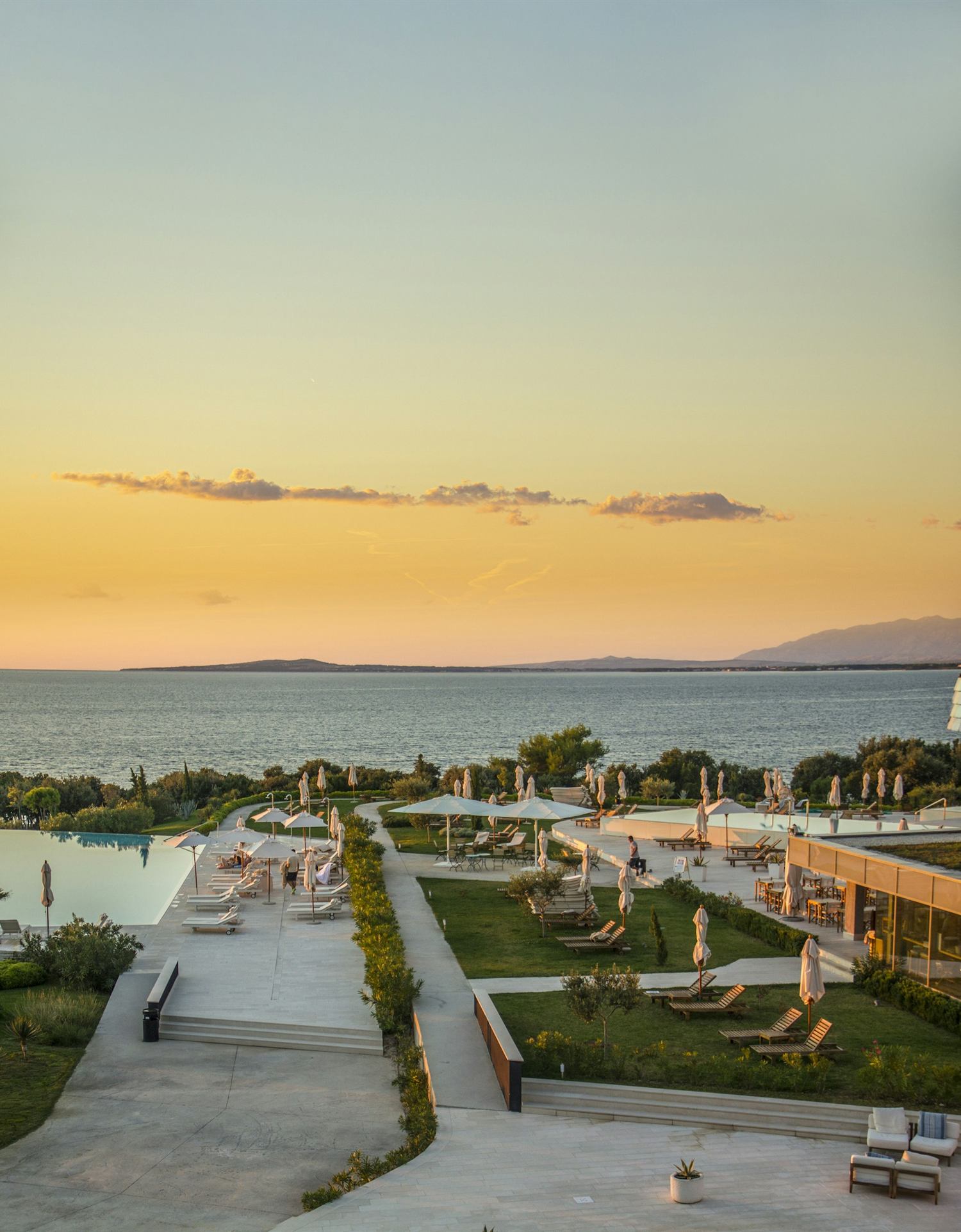 A quiet resort terrace and pool above the sea as the sun goes down