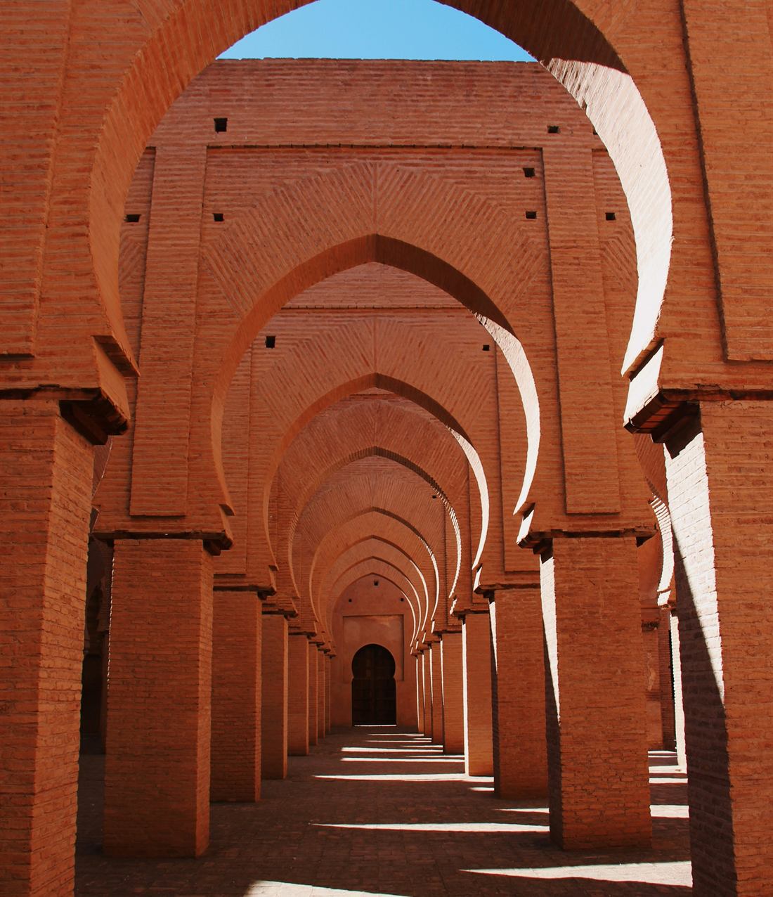 A long arcade of terracotta arches receding into warm light