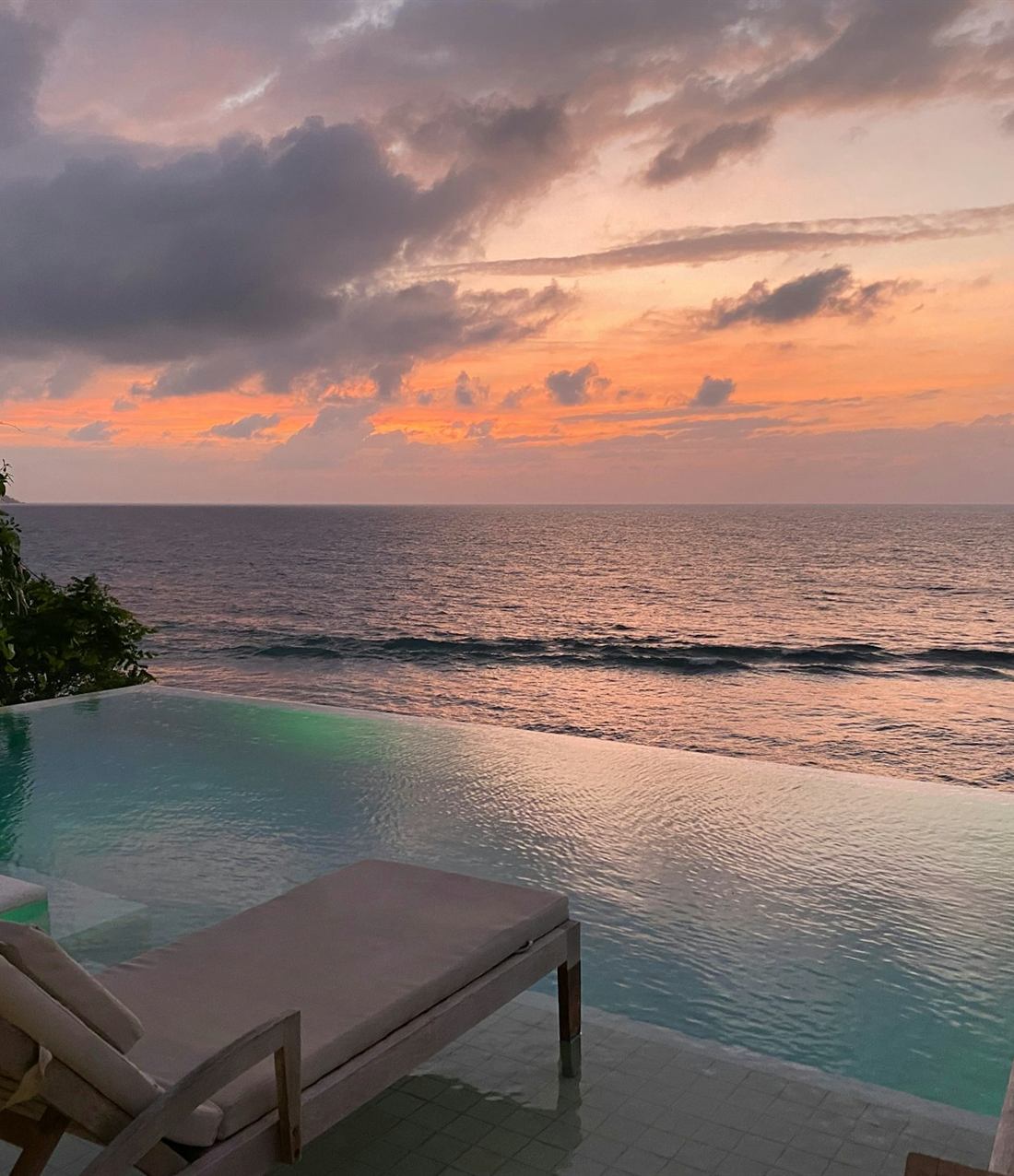 An infinity pool meeting the sea at sunset