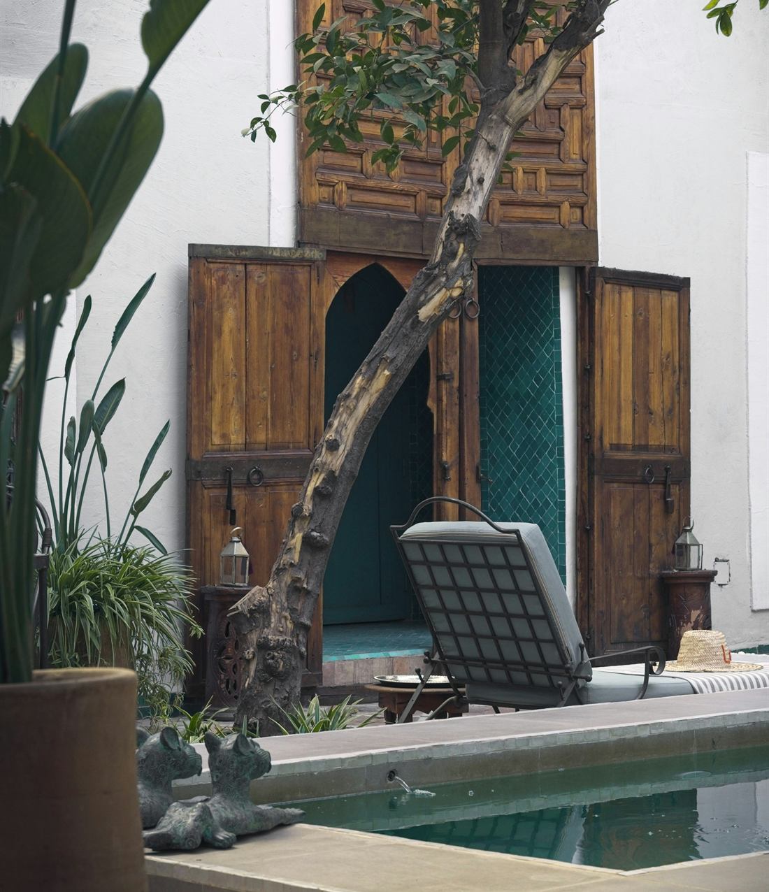 A riad courtyard pool beside tall carved wooden doors
