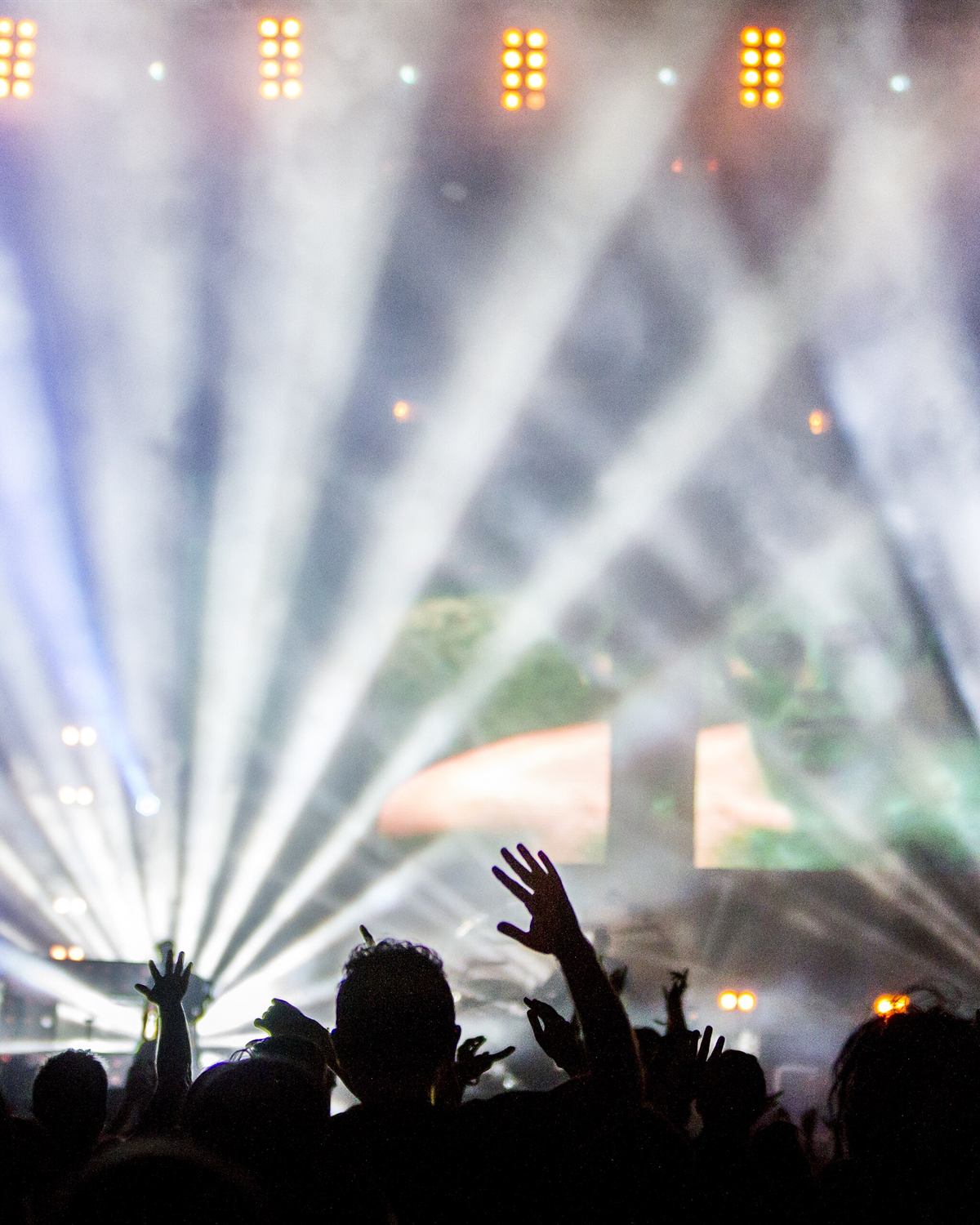 Beams of light and smoke above a crowd with their hands raised